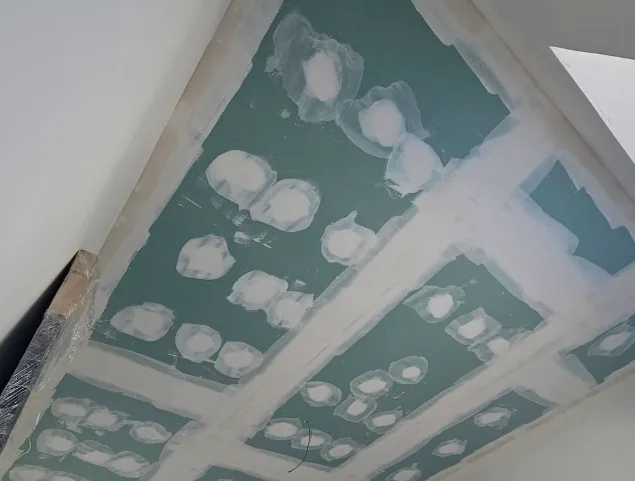 Ossature métallique et isolant en cours de pose au plafond